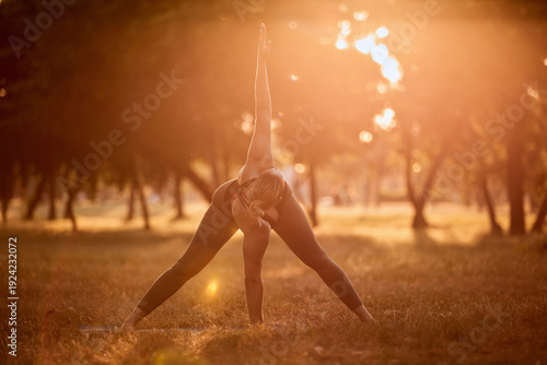 Woman practicing yoga and stretching in the park on a hot sunny summertime day.