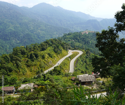 Фотография Winding mountain road with hairpin turn through lush green hills