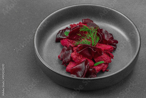 Vegan beetroot pasta with fresh dill and mint served in a trendy dark ceramic bowl