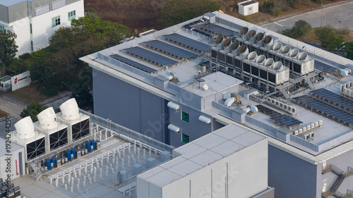 Aerial view of a modern industrial building, adorned with solar panels and cooling towers, casting shadows under the afternoon sun, Datacenter, Chang Wat Chon Buri, Thailand.