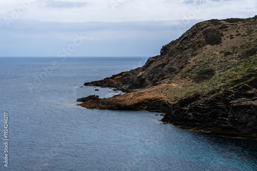 Wallpaper Mural Coastal landscape of Menorca with cliffs meeting the sea under a cloudy sky. Torontodigital.ca