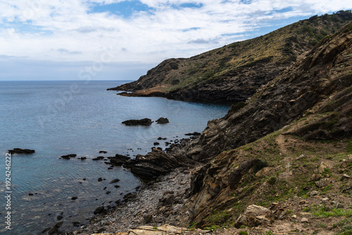 Wallpaper Mural Coastal landscape of Menorca with cliffs meeting the sea under a cloudy sky. Torontodigital.ca