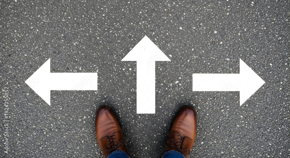 Fototapeta premium Person standing on asphalt road with white arrows pointing in different directions indicating choices