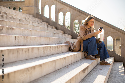 Woman sits on steps and use...