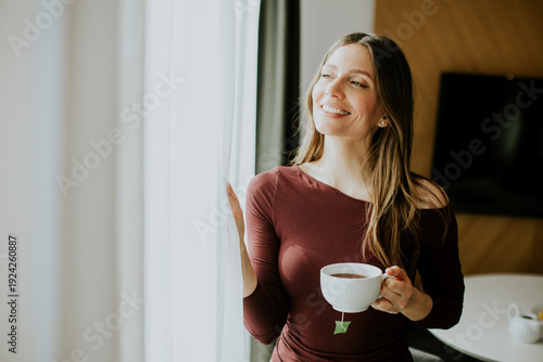 Woman enjoys tea while look...