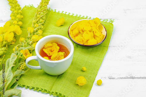 Cup of herbal tea with mullein flowers and leaves. Natural light, alternative medicine