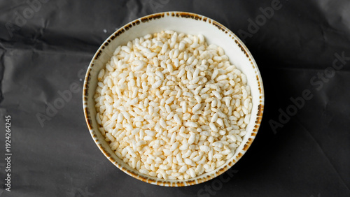 Slika na platnu Puffed rice in ceramic bowl on dark background minimalist food photography