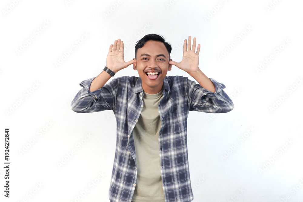 Fototapeta premium Asian man wearing a plaid shirt with a playful expression is making a funny face on an isolated white background.