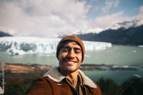 Smiling traveler takes a selfie with a glacier in the background