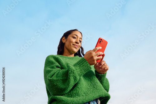 Pleased woman uses her mobile phone outdoors