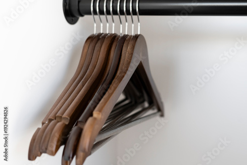 Wooden hangers on a black rod in closet