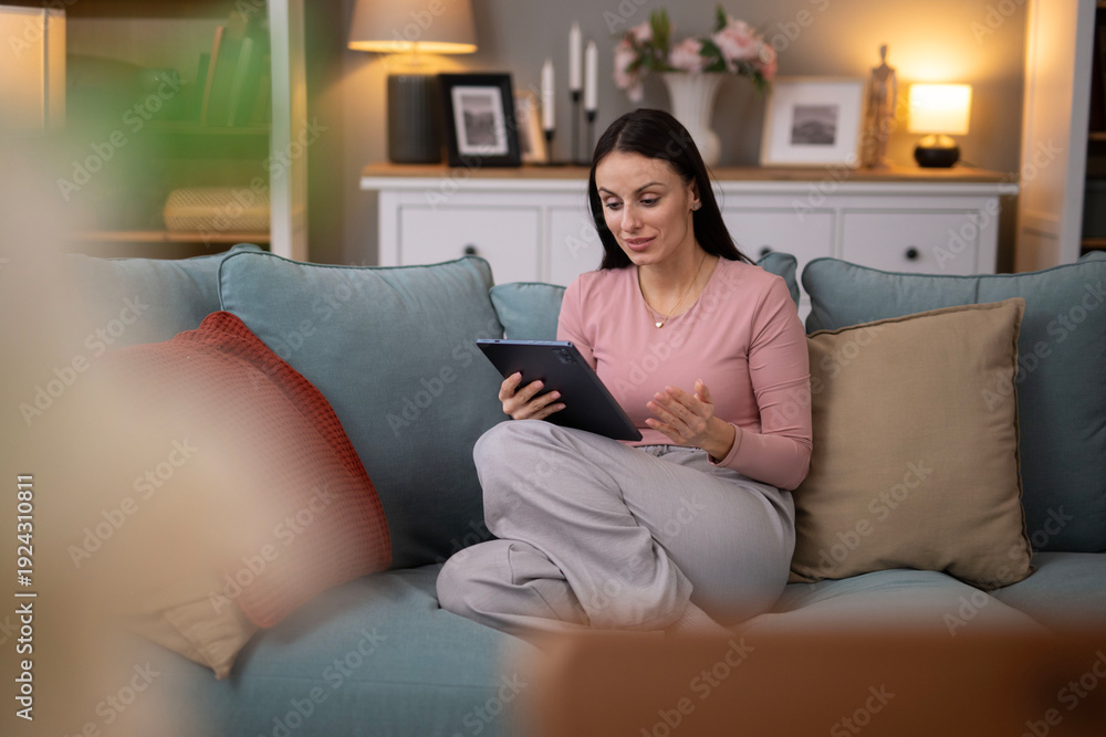 Obraz premium Woman making video call using tablet on sofa