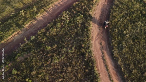 Vista aérea de uma motocicleta em uma estrada de terra deserta.