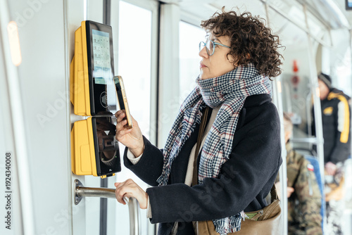 Tableau sur toile Passenger taps touch screen ticket machine inside tram, smart transit concept