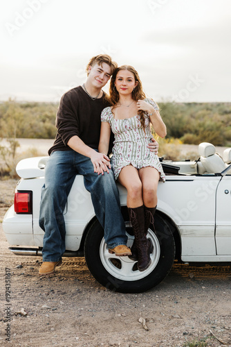 Young couple sitting on side of convertible 