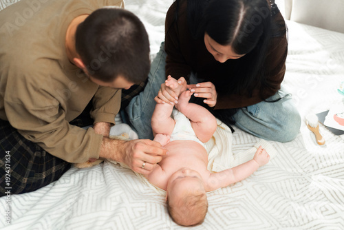 Parents changing diaper of their newborn baby on a bed, close-up view