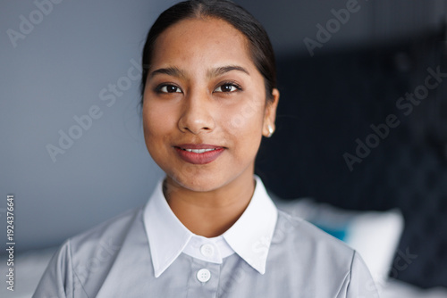 Portrait of adult smiling latin maid looking at camera in hotel room
