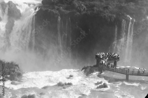 Tourists on a viewpoint observe the powerful Iguazu Falls. 