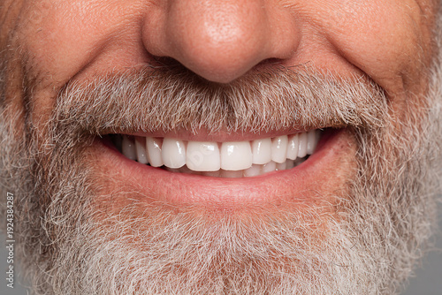 A man with a beard and a bright white smile beams in this close up shot
