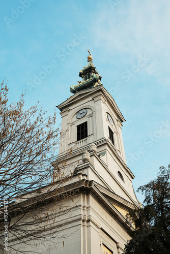 Historic clock tower with ornate spire rising against clear blue sky in Belgrade, highlighting baroque architecture and urban landmark silhouette.