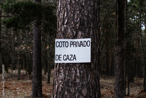 Warning sign in Spanish reading “Coto privado de caza” (Private hunting area) placed in a rural forest environment.