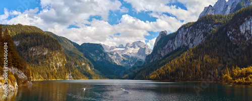 Scenic autumn panorama of Lake Gosausee with tourist boats and the Dachstein massif in the background, Austria.