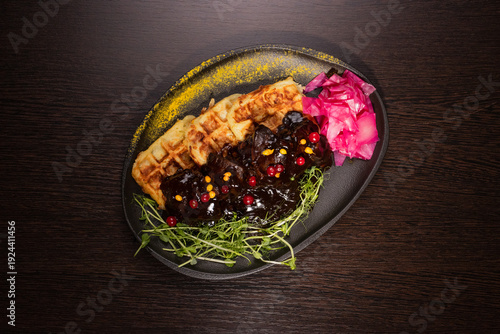 Fried meat with potato waffles and herbs on a plate