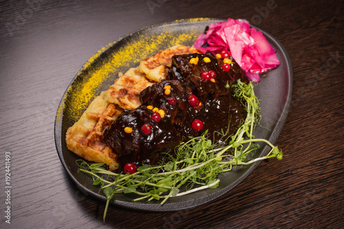 Fried meat with potato waffles and herbs on a plate