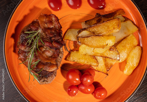 Steak with fried potatoes and tomatoes on a plate
