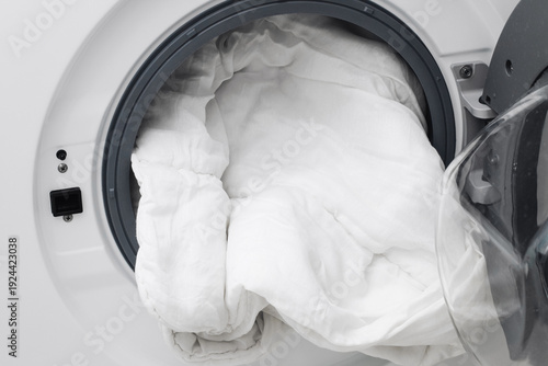 фотографія White bedding inside washing machine drum