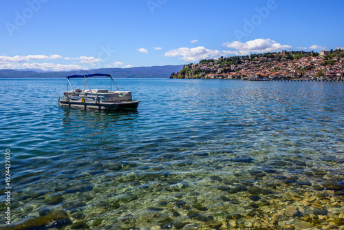 Foto Undisturbed, blue waters of Lake Ohrid reflect the bright atmosphere as a pontoon boat rests gently