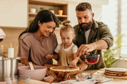 Fotografie Family baking cake together in kitchen at home