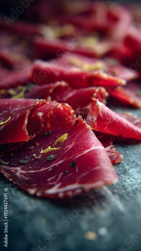 Exquisite Thinly Sliced Cured Meat Delicacy with Aromatic Spices on a Dark Rustic Surface, Ready to Serve.