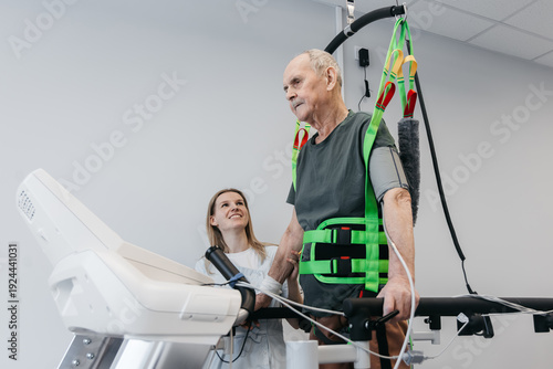 Obraz na plátne Senior man recovering movement with therapist help using safety harness equipment