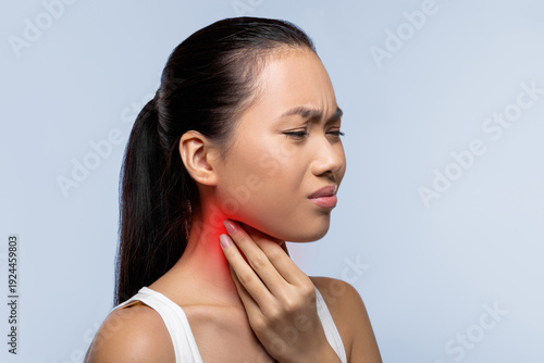 Photos A woman stands in an indoor space, holding her neck with a pained expression