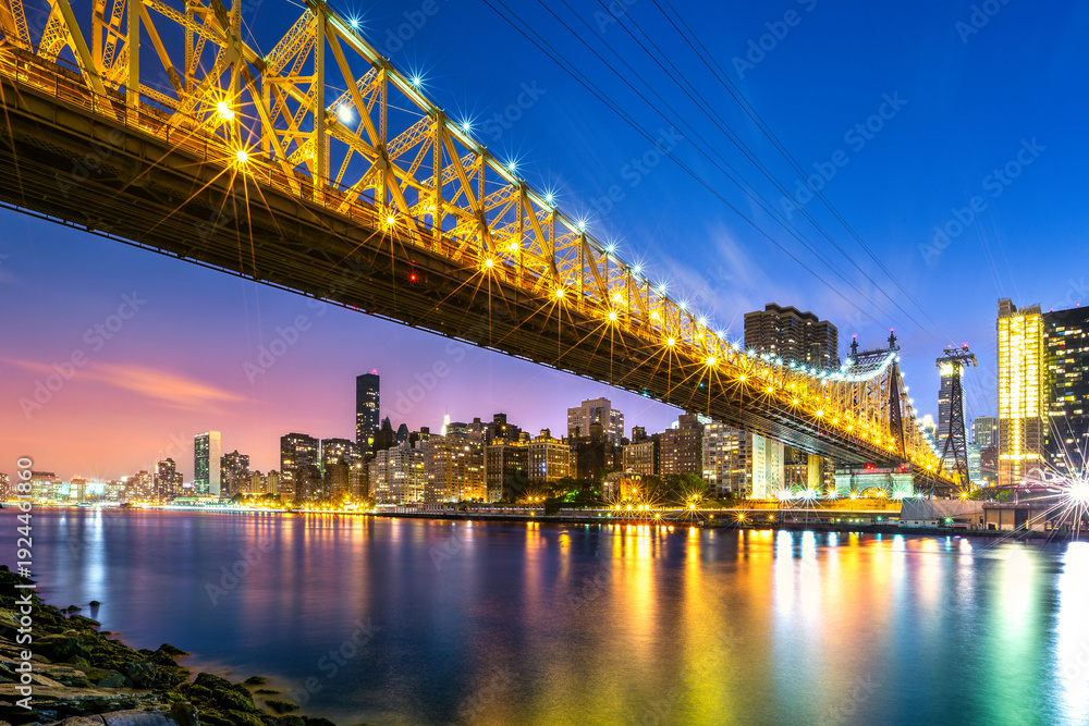 Fototapeta premium Long exposure of Queensboro bridge and its cable car line, at dusk viewed from Roosevelt island, New York