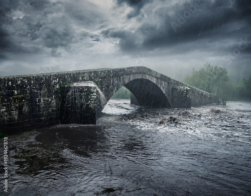 Stone bridge in storm and flood with swollen river
