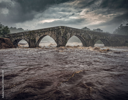 Stone bridge in storm and flood with swollen river