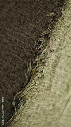 Close up of torn fabric upholstery with visible scratch marks and frayed threads caused by cat claws. Damaged textile surface showing wear and tear, suitable for pet behavior, home damage, and texture