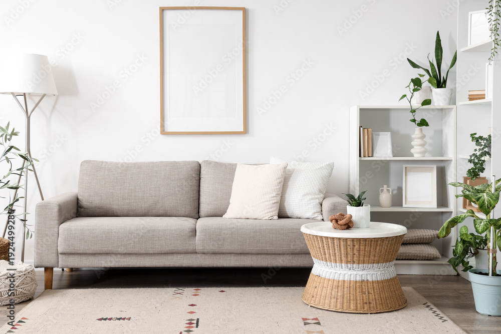 Fototapeta premium Interior of light living room with sofa, blank frame and green plants
