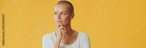 Quadro em tela Young hairless woman, thinks over problem, remembering something, looking at camera isolated on yellow background in studio