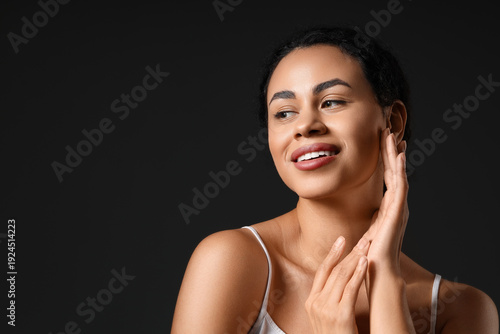 Foto Young African-American woman with healthy skin on dark background