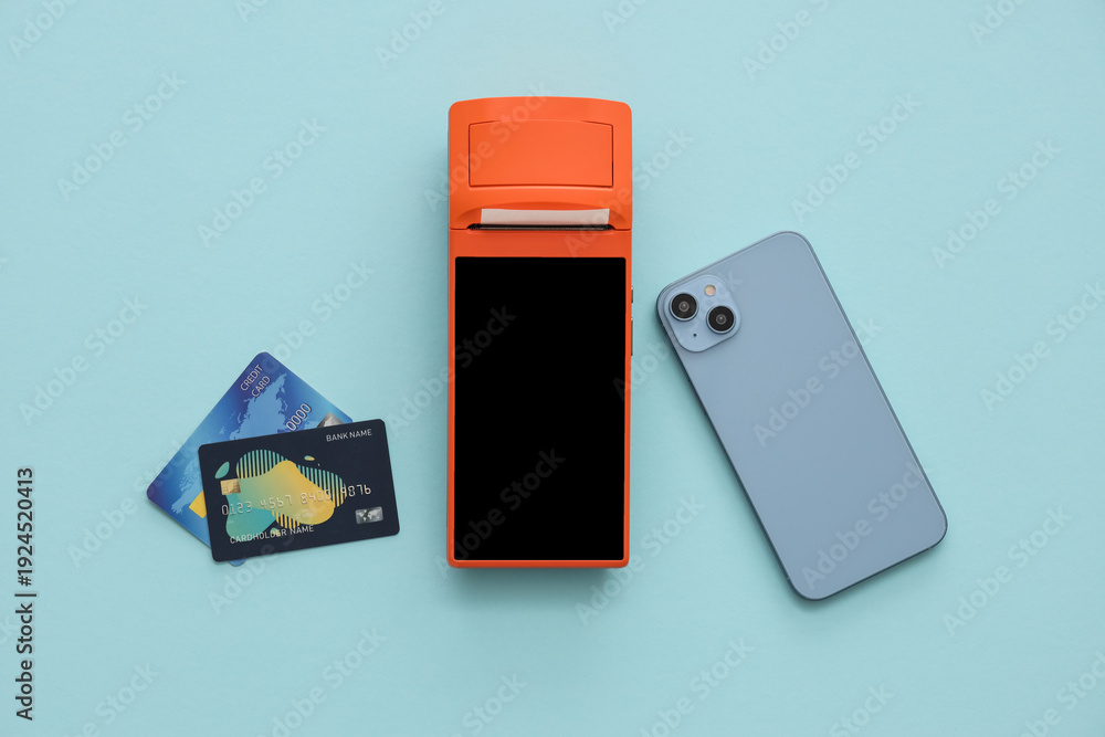 Obraz premium Payment terminal with credit cards and mobile phone on blue background
