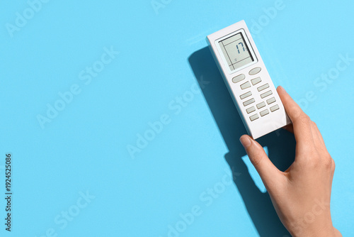 Wallpaper Mural Female hand with air conditioner remote control on blue background Torontodigital.ca