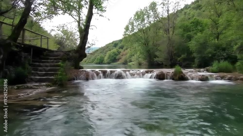 A breathtaking natural river landscape featuring multiple small waterfalls cascading over mossy rocks surrounded by lush green forest and distant hills evoking a sense of peace and tranquility in the.