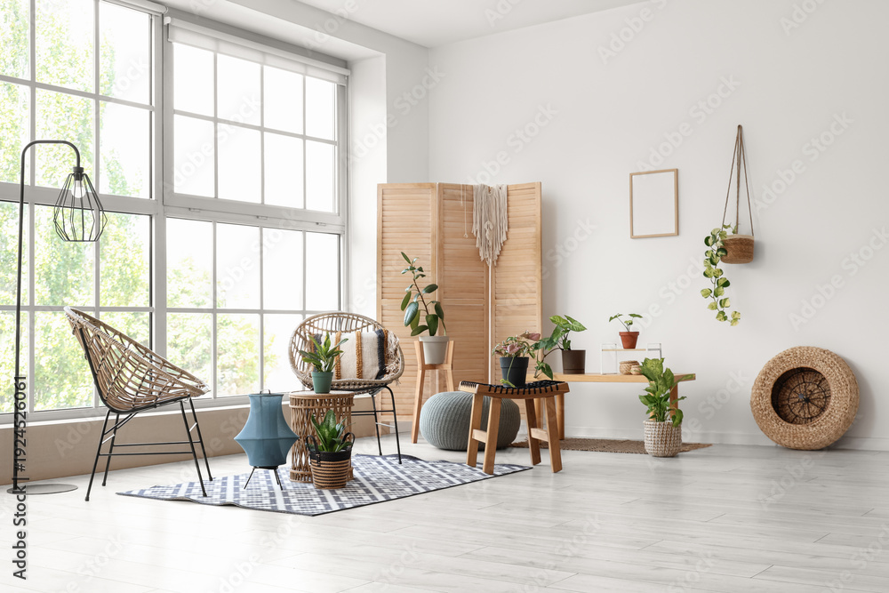Fototapeta premium Interior of light room with wicker armchairs, tables and green plants