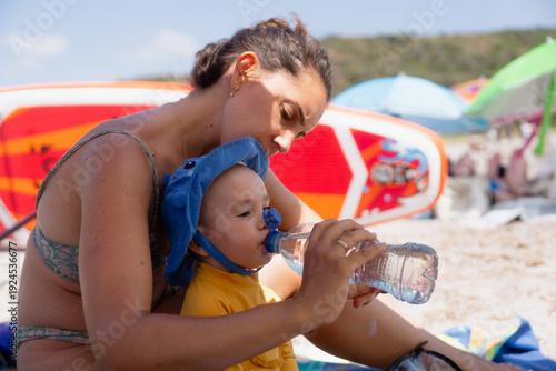 Mother hydrating baby on summer beach vacation
