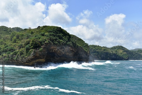 Bild auf Leinwand Beautiful view of Timang beach in Yogyakarta, Indonesia with blue sea, crashing waves, green rocky cliffs and cloudy blue sky