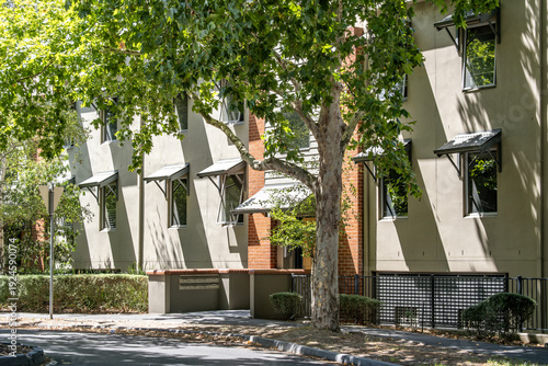 Quadro em tela Residential apartment building exterior along a leafy suburban street with urban greenery offering shade