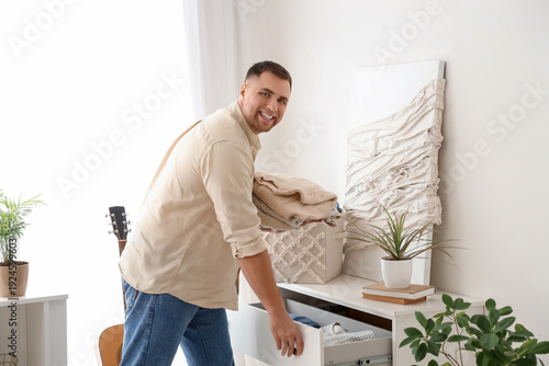 Young man putting folded cl...